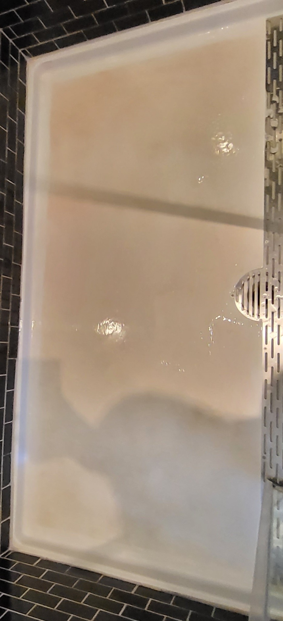 Shower pan before cleaning with visible buildup